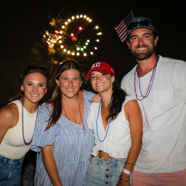 4 people in red white and blue standing in front of a smiley face firework