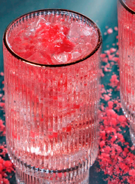 Red pop rocks drink in a short glass on a blue background.