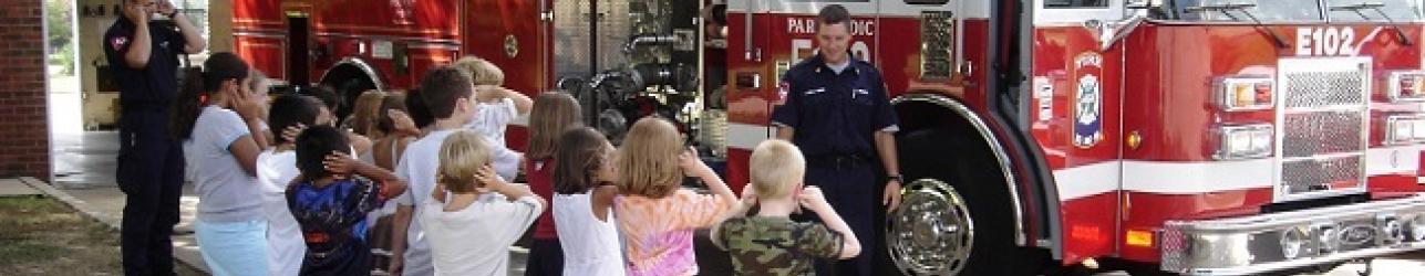 Kids covering their ears in front of a fire truck