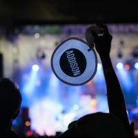 Stage with silhouette of arm holding promotional fan.