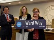 Lori Ward holding a street sign that says Ward Way
