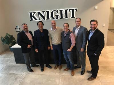 group of people in an office in front of knight sign