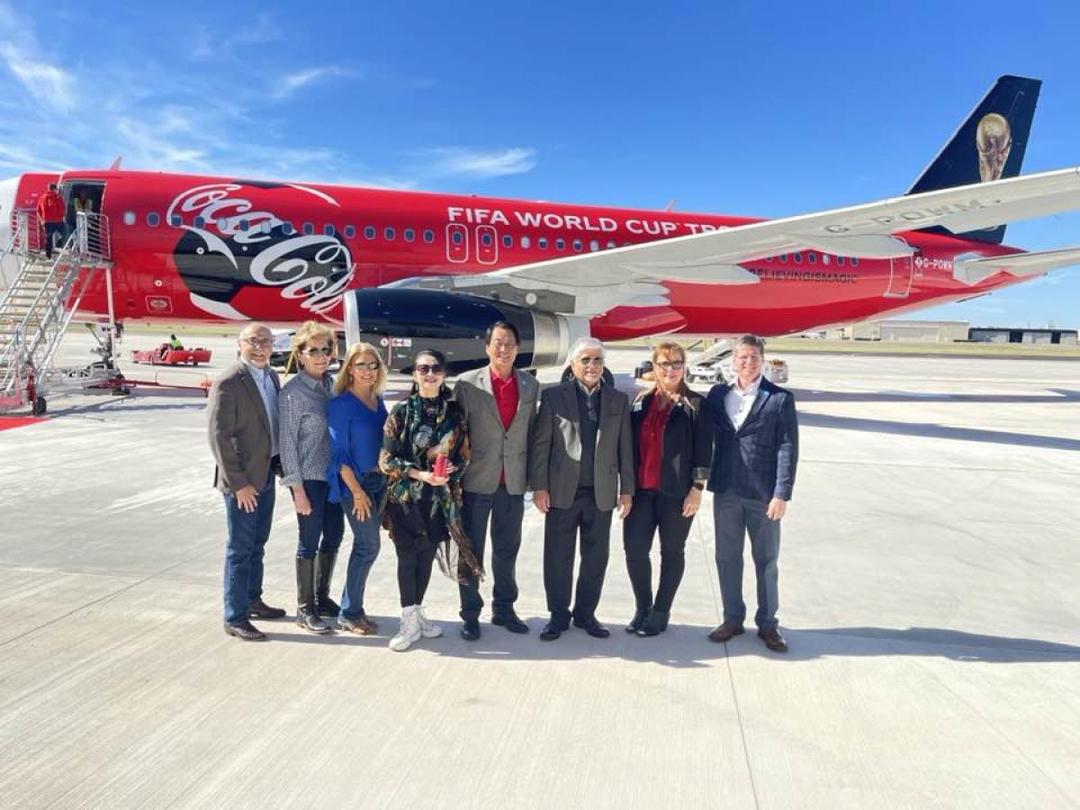 Addison City Council Members  standing next to the Coca Cola airplane that carries the FIFA Soccer trophy on its global tour